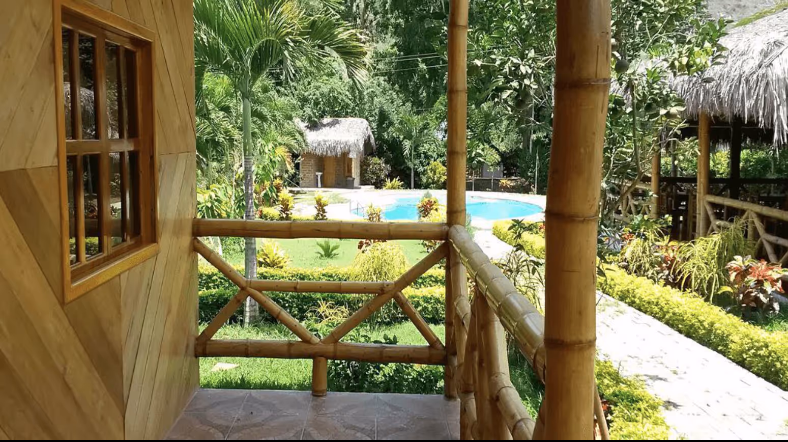 Jardín con pabellón de bambú y palmeras tropicales en la Hostería Arandú