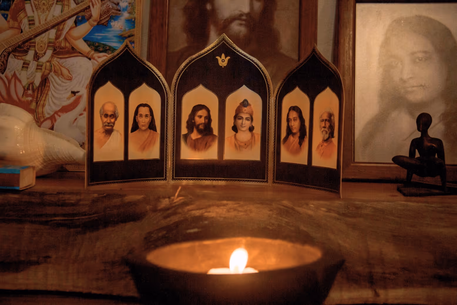 Altar espiritual con vela encendida y retratos de maestros en el Radha Krishna Vatika Ashram