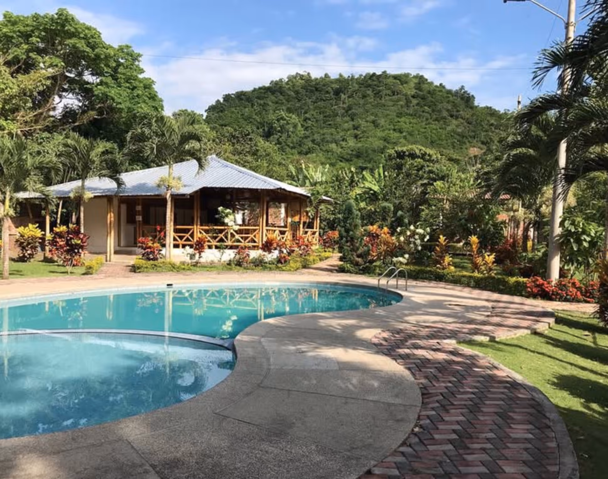 Vista desde la cabaña de bambú con jardín tropical y piscina de la Hostería Arandú