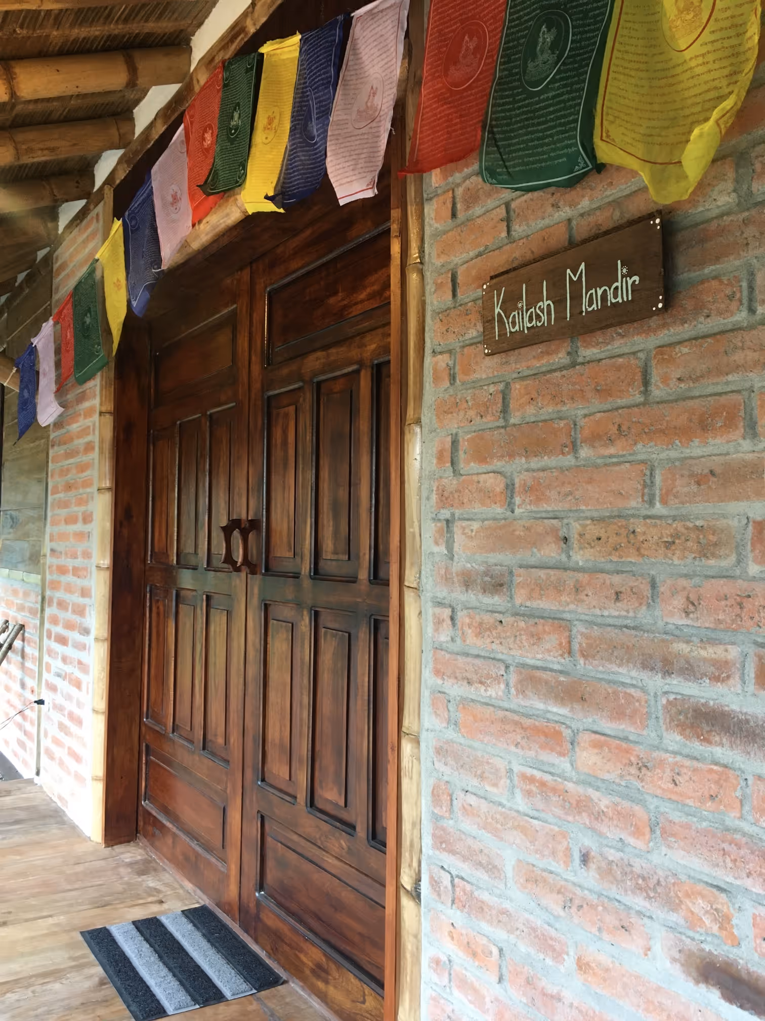 Entrada al Kailash Mandir con banderines de oración tibetanos en el Ashram